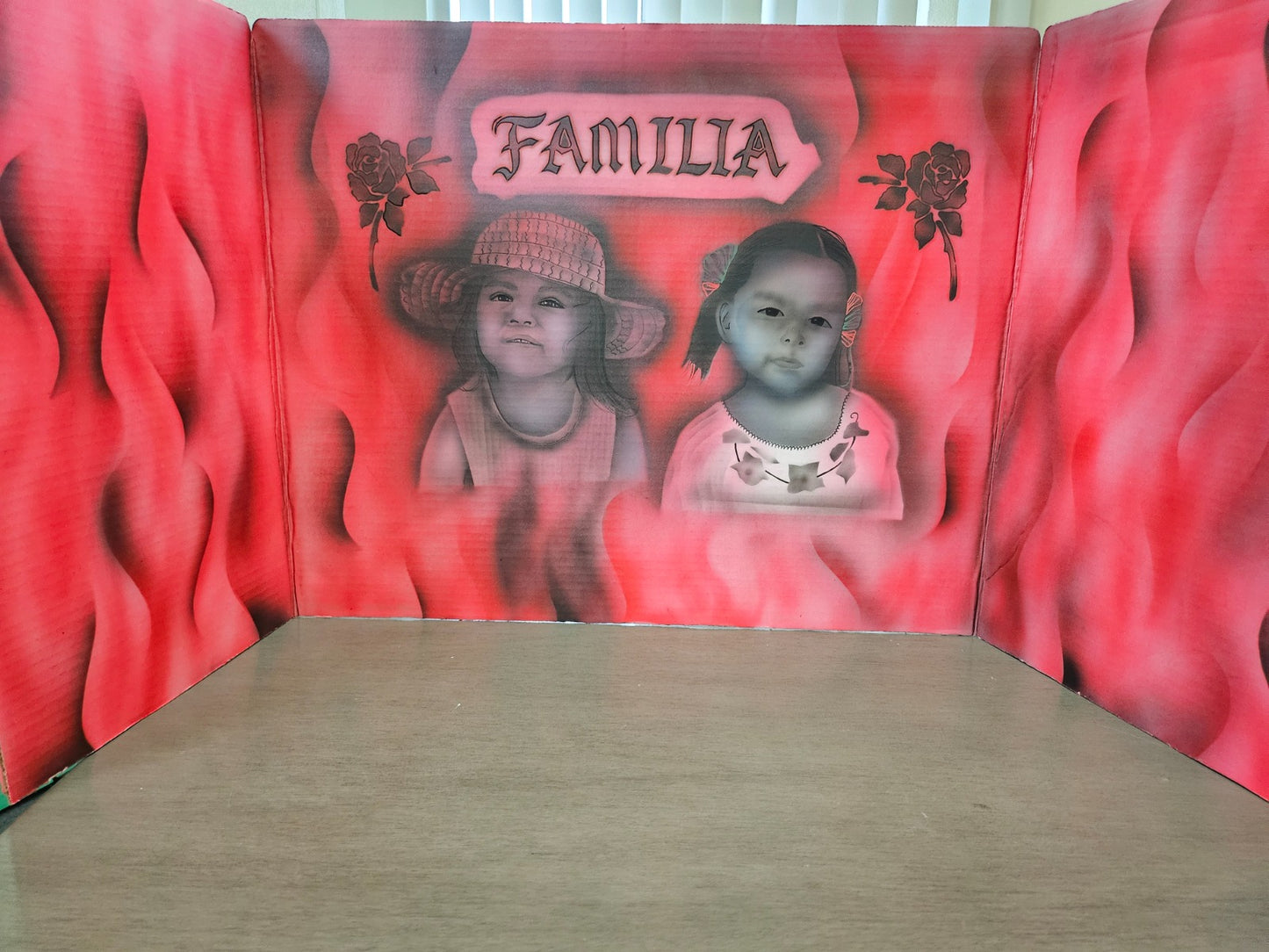 Red decorative wall with two children's portraits and the word 'FAMILIA' above them.